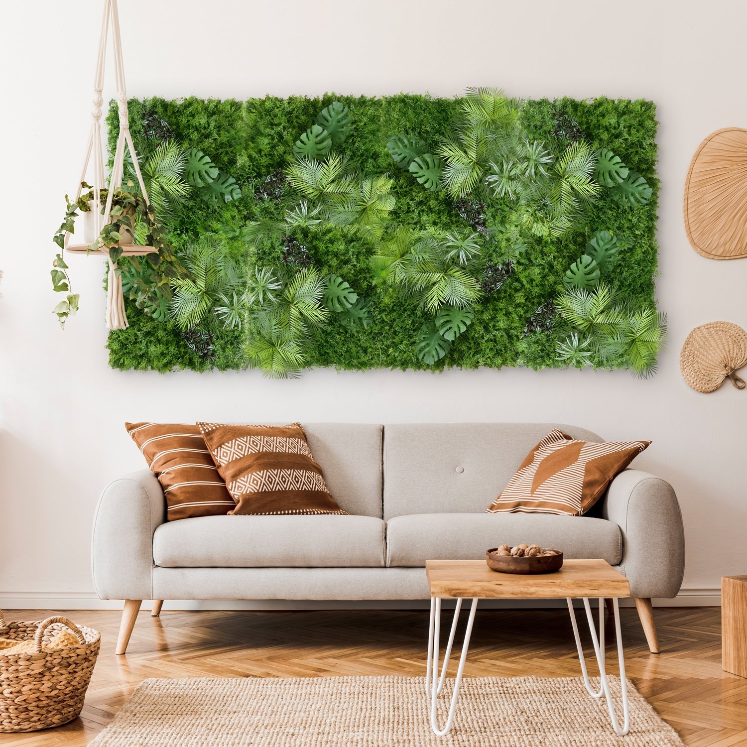 A cozy living room features a gray sofa with patterned cushions and a wooden coffee table with a bowl. The Tropical Green Wall mural from Landmark Decor adds vibrancy along with lush hanging plants, while wicker baskets enhance the decor and light wood flooring completes the fresh look.
