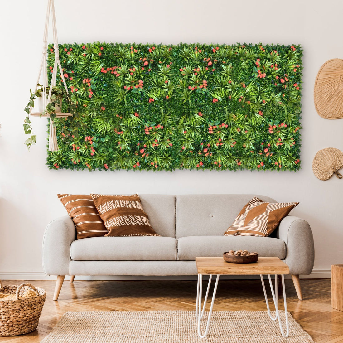 A cozy living room features a light gray sofa with patterned cushions. The Landmark Decors Tropical Floral Wall, brimming with red flowers and various plants, adds vibrancy to the space. A modern coffee table and woven baskets enhance the warm, natural ambiance.