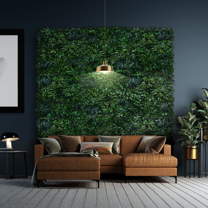 The living room showcases the Emerald Sanctuary, a brown sectional sofa with assorted cushions on a gray carpet. A lush vertical ivy garden by Landmark Decor adorns a dark wall, illuminated by a modern hanging lamp. A side table with a lamp and potted plant completes the look.