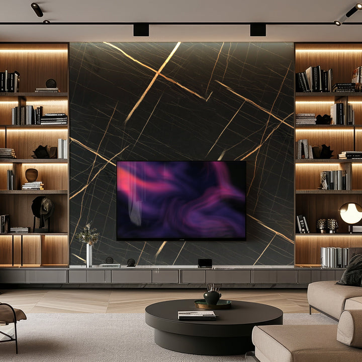 A modern living room showcases a large TV on Landmark Decors Midnight Gold Marble Durable PVC Wall, known for its dark marble with gold veins. Illuminated shelves display books and decor, while a round coffee table with a vase stands on a textured rug over light wood flooring, enhancing the luxurious feel.