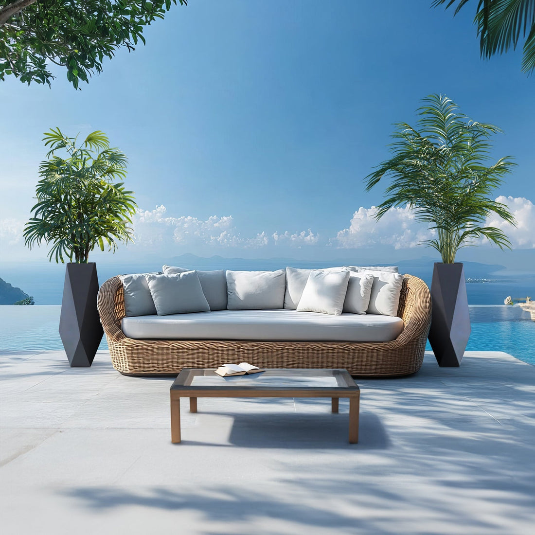An outdoor patio showcases a wicker sofa with white cushions beside a pool. The scene is flanked by two Ombre Intrecciate Planters from Landmark Decor, merging luxury and nature. A glass-top coffee table sits in front, set against a backdrop of mountains and clear blue sky.