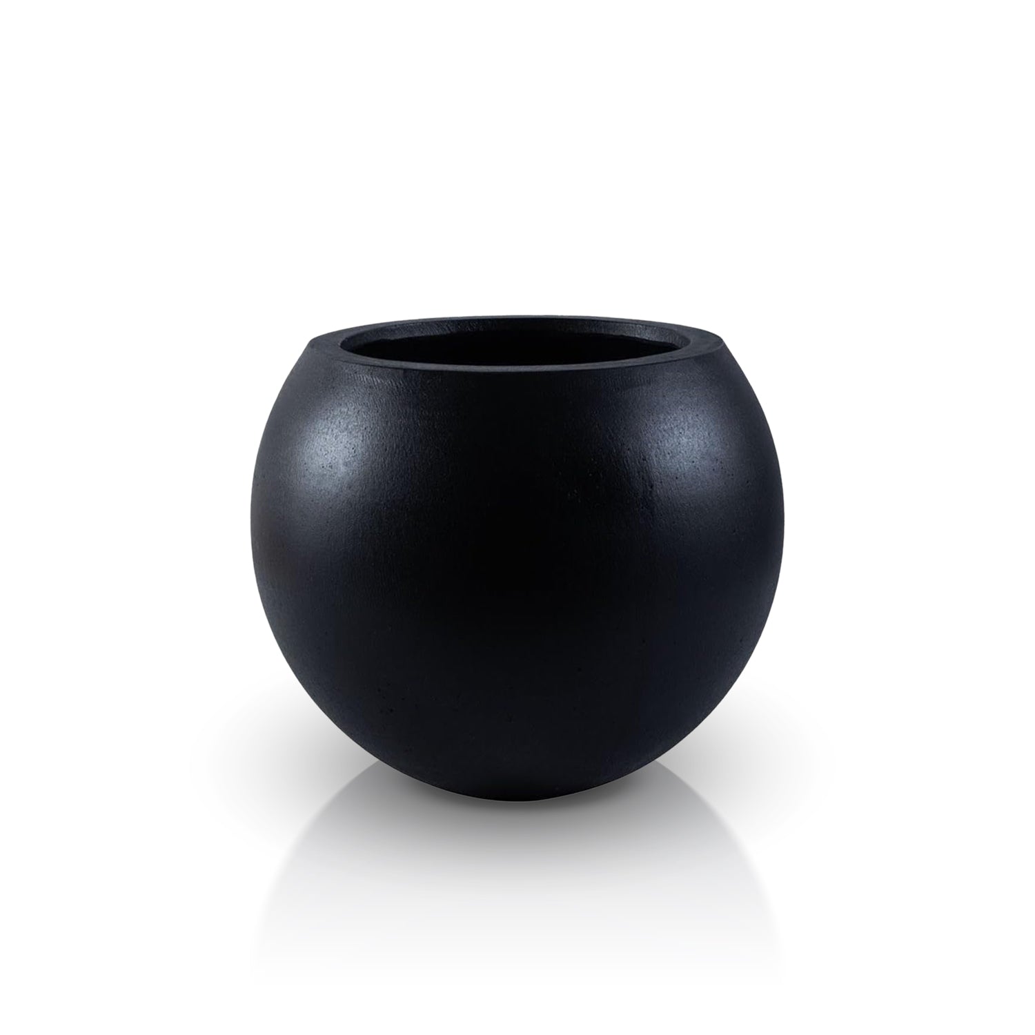 The Urban Vessel Planter by Landmark Decor is a smooth, round, black matte handmade planter with a wide opening. Its minimalist design emphasizes simplicity and elegance, seamlessly blending luxury and nature as it sits on a reflective surface.