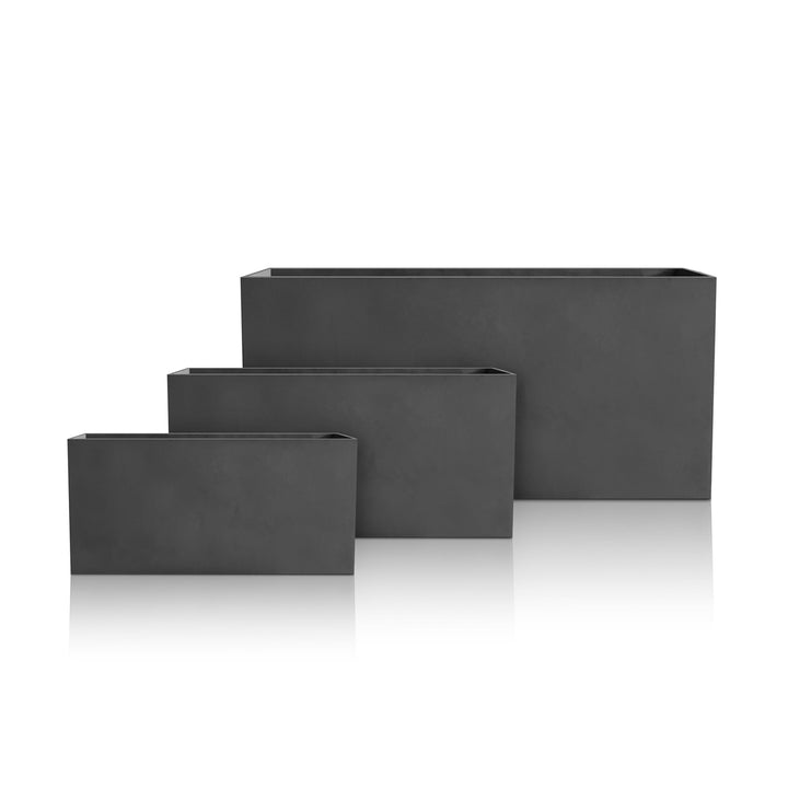 The Minimalist Oasis Planter by Landmark Decor features three black rectangular handmade planters, each in varying sizes arranged ascendingly from left to right, exuding luxury and nature. Displayed on a reflective white surface, they create a striking visual appeal.