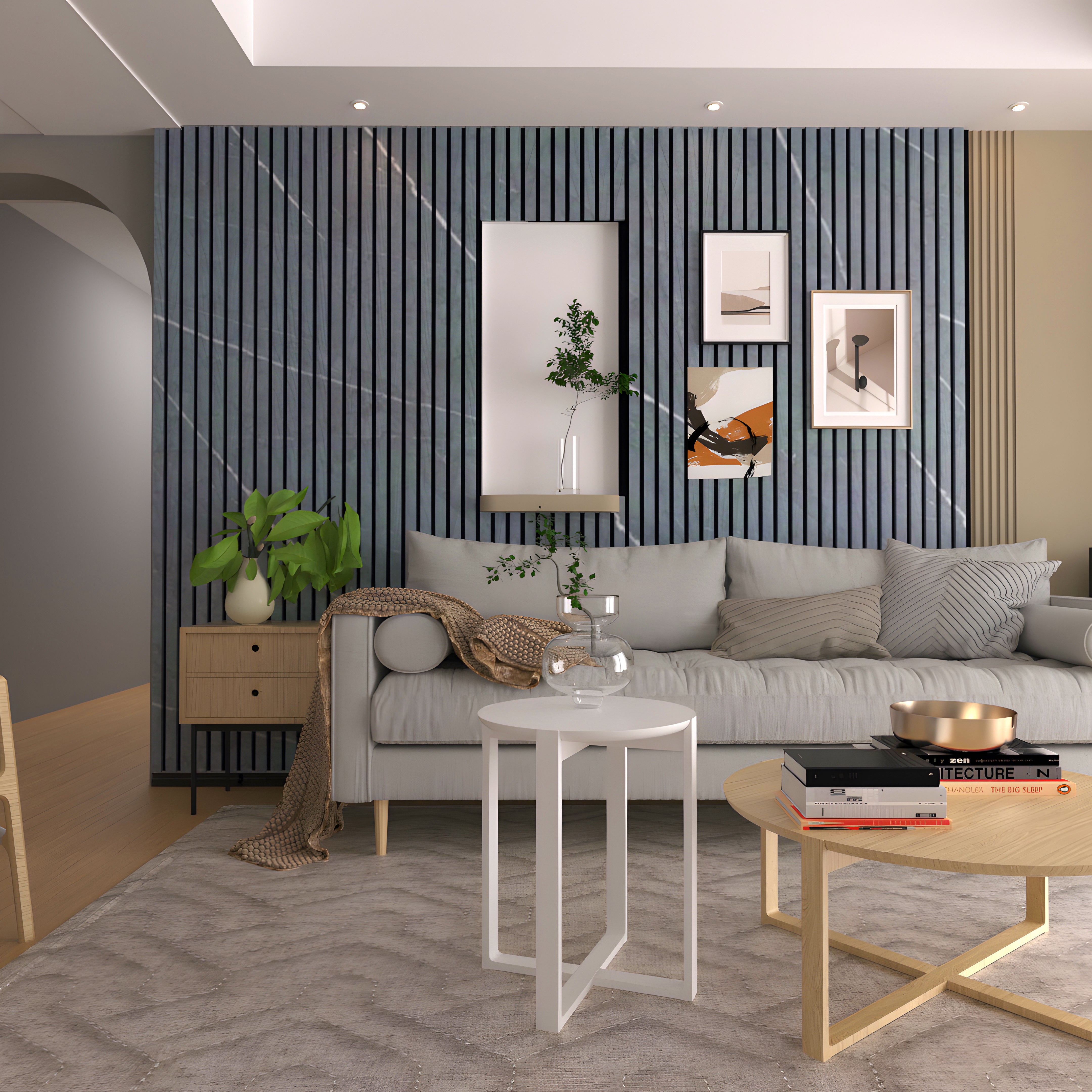 A modern living room showcases a light gray couch, decorative cushions, and a throw. The feature wall is a Landmark Decor Black Marble WPC Fluted Slat Wall Panel with art and recessed shelves holding plants. A round wooden coffee table and white side table rest on a textured rug in warm, neutral tones.