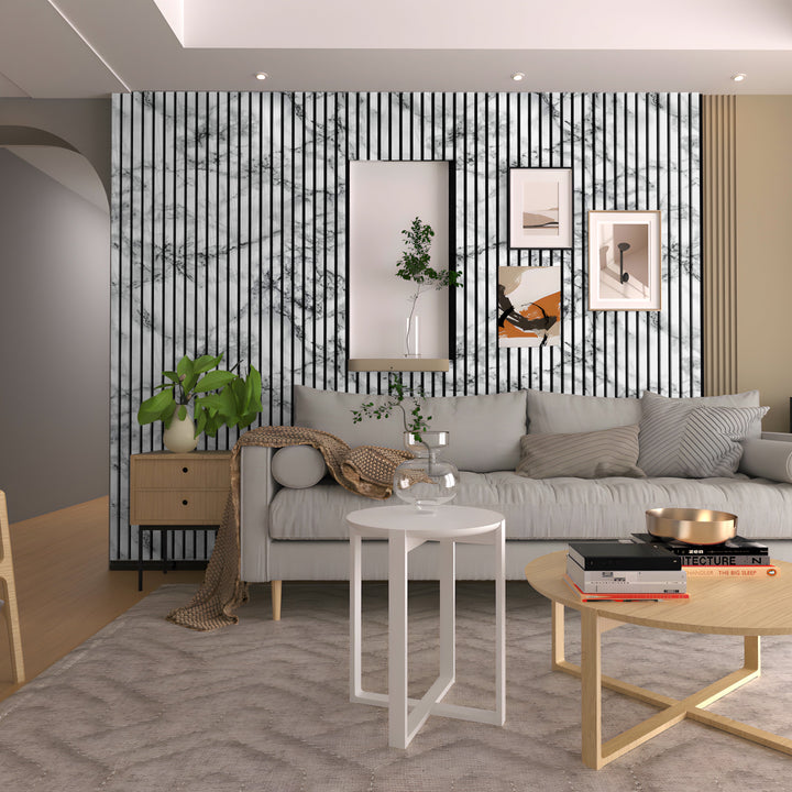 In a contemporary living room, a light gray sofa pairs with Landmark Decors White Marble WPC Fluted Slat Wall Panel. A round white side table supports a glass vase, while framed art and potted plants add interest. Warm lighting and minimalist decor enhance the cozy atmosphere beautifully.