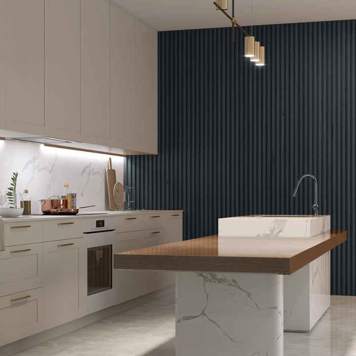 A modern kitchen with white cabinets features a marble island. An elegant accent wall is created using Space Gray WPC Fluted Slat Wall Panels by Landmark Decor. A sleek stovetop and oven are built into the counter, complemented by copper and wooden utensils. Three pendant lights brighten the space.