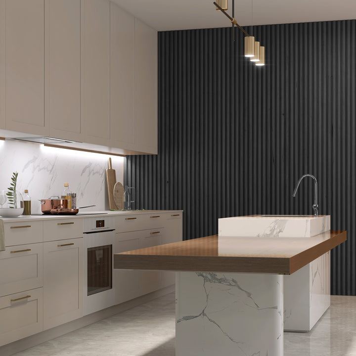 Modern kitchen featuring Landmark Decors Black WPC Fluted Slat Wall Panels, white cabinets, and marble countertops. A marble island with a wood top and built-in sink extends into the room. Brass pendant lights hang above, with neatly arranged kitchenware along elegant interior panels.