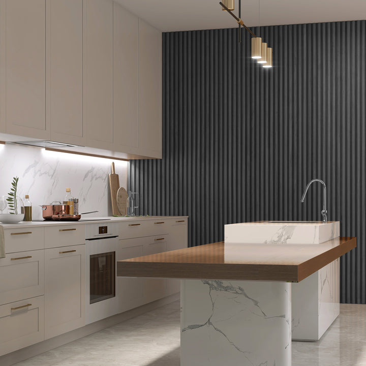 A modern kitchen featuring white cabinets, a marble countertop, and a large island with a wooden top. The space includes three pendant lights, a built-in oven, and an accented wall with Landmark Decors Dark Gray WPC Fluted Slat Wall Panel for added texture. Decorative items and a sink adorn the island.